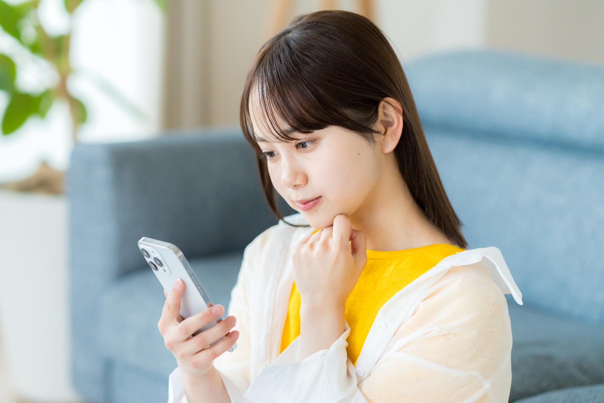 スマートフォンを見ながら考える女性